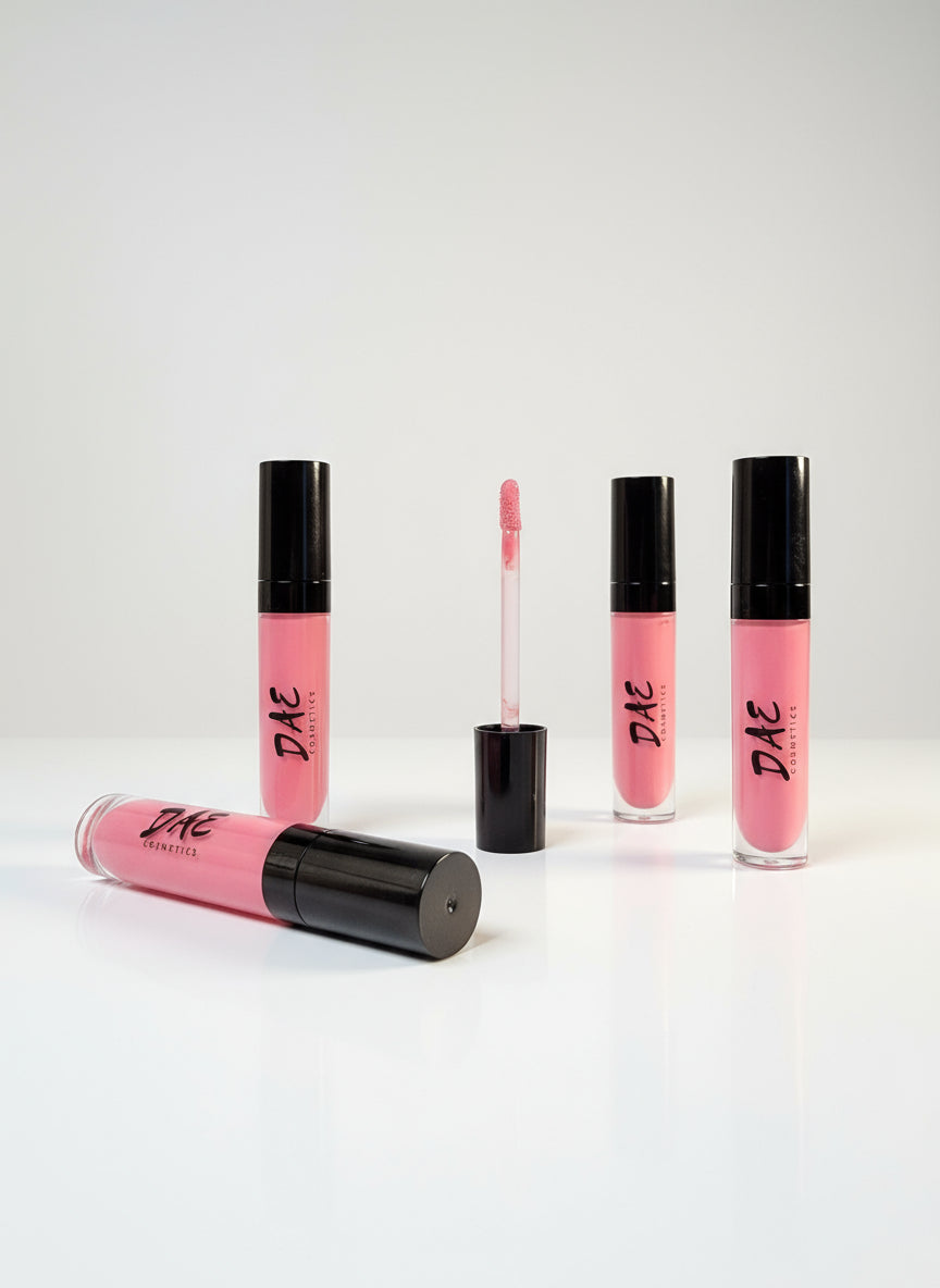 Pink lip glosses with black caps on a gray surface